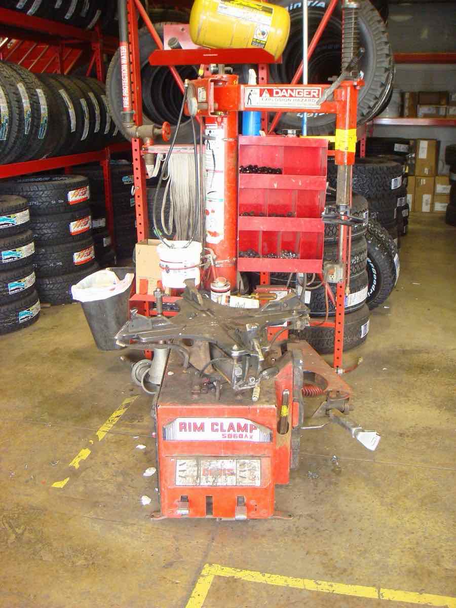 Tire changer machine in a tire shop with new tires racked behind it