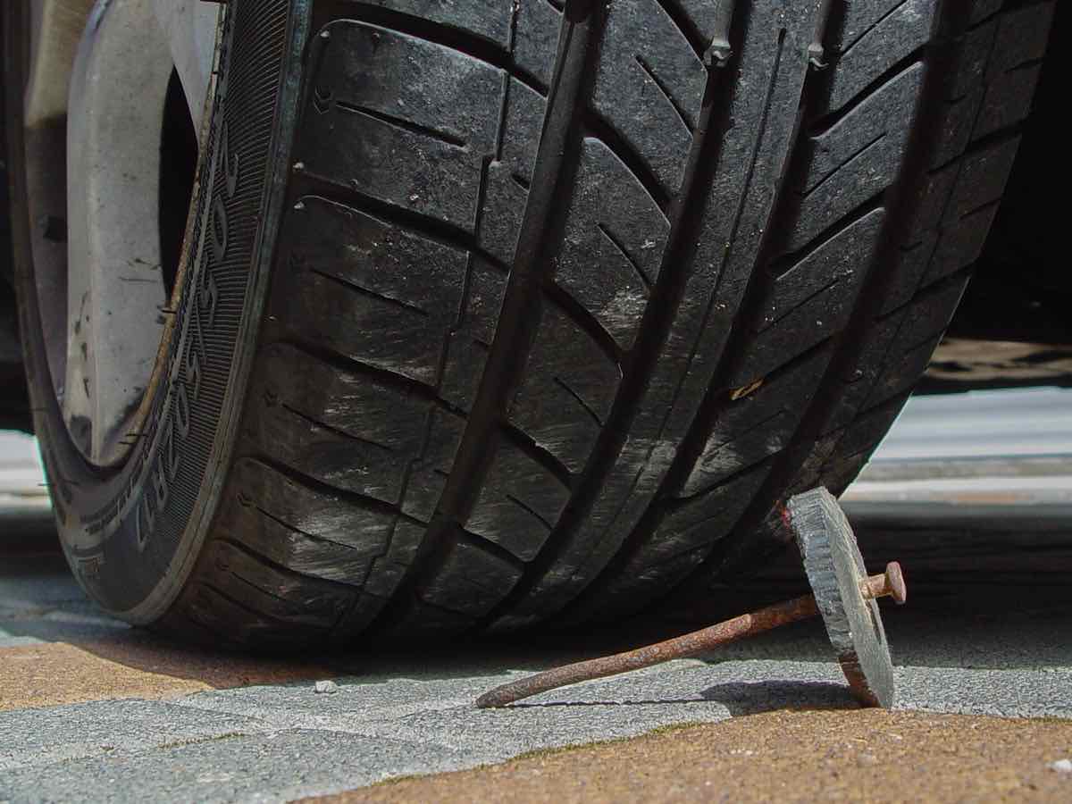 Nail lying next to a car tire on the road