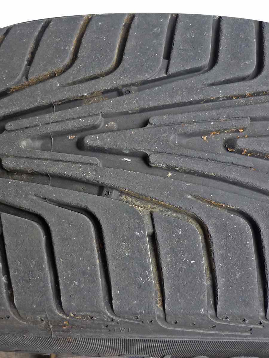 Car tire tread with a raised tread wear indicator bar between the grooves